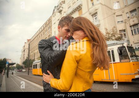 Giovane uomo che abbraccia la giovane donna in città Foto Stock