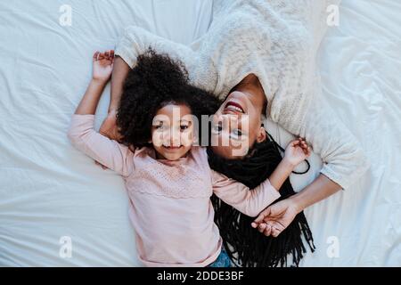 Vista ad alto angolo della madre e della figlia che si trovano sul letto a casa Foto Stock