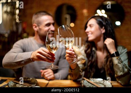 Gli amici si guardano l'un l'altro mentre tostano un drink al ristorante Foto Stock