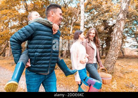 Padre che porta il figlio piggyback mentre madre e figlia camminano dentro Parco di Cannock Chase Foto Stock