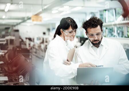 Scienziati di sesso maschile e femminile che discutono su laptop in laboratorio Foto Stock