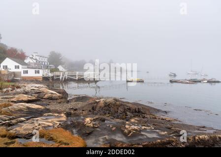 Baia avvolta nella nebbia mattutina con barche ancorate e legno jetties in autunno Foto Stock