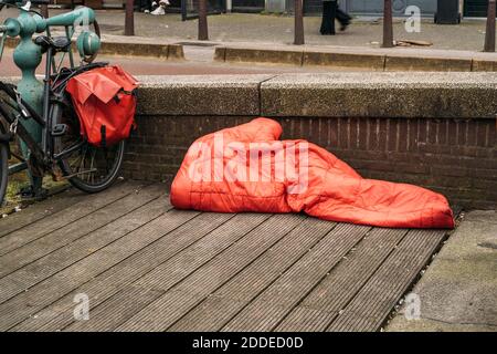 Gli senzatetto dormono sotto una coperta rossa nel centro della città europea. Foto Stock