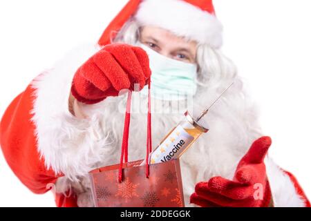 Babbo Natale con maschera viso offre regalo di Natale un vaccino iniezione. Foto Stock