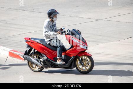 SAMUT PRAKAN, THAILANDIA, 27 2020 LUGLIO, UN uomo con il telefono cellulare in mano guida una moto Foto Stock