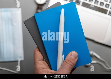 notebook blu chiuso in mano sopra il piano di lavoro Foto Stock