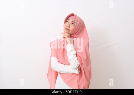 Un ritratto della donna musulmana asiatica felice che indossa un velo o un hijab pensando a un'idea o sognando o presentando e guardando lo spazio vuoto. Isolato su whit Foto Stock