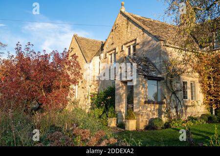 Cotswold casa in pietra in autunno pomeriggio luce del sole nel villaggio di Sherborne, Cotswolds, Gloucestershire, Inghilterra Foto Stock