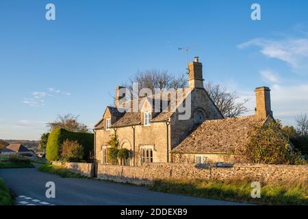 Cotswold casa in pietra in autunno pomeriggio luce del sole nel villaggio di Sherborne, Cotswolds, Gloucestershire, Inghilterra Foto Stock