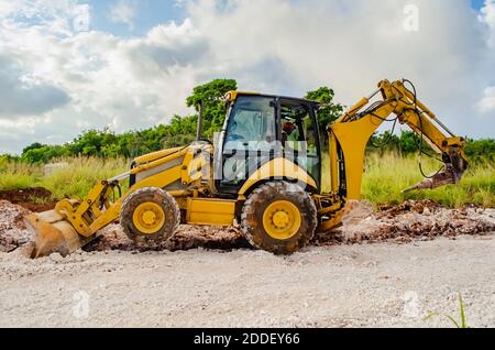 Durante la costruzione di una carreggiata, un martello pneumatico attaccato al braccio di un retroescavatore viene utilizzato per rompere la roccia incorporata durante il processo di scavo tre Foto Stock