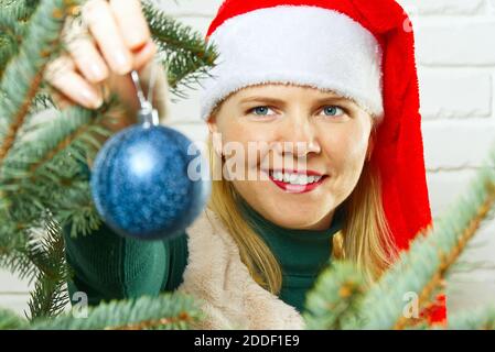 Bionda bella donna che decorano l'albero di natale con le sfere blu di decorazione ornamenti. Foto Stock