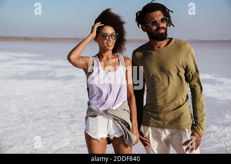 Giovane coppia africana che ama camminare lungo la riva del mare, tenendo le mani Foto Stock