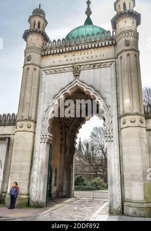 Nel centro della città una donna si trova sotto l'indiano Entrata ad arco in stile Rajl ai giardini del Royal Pavillion, un tempo residenza reale durante la re Foto Stock