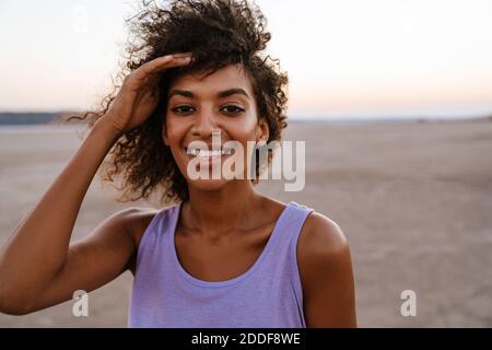 Immagine di felice donna afroamericana che posa e sorride macchina fotografica nel deserto Foto Stock