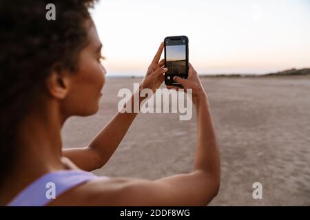 Immagine di felice afroamericana scattando foto sul cellulare nel deserto Foto Stock