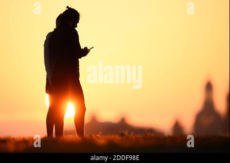 Dresda, Germania. 25 Nov 2020. La gente si distingue all'alba sullo sfondo della città vecchia con la Frauenkirche (r) come silhouette scure contro il cielo. Credit: Sebastian Kahnert/dpa-Zentralbild/dpa/Alamy Live News Foto Stock