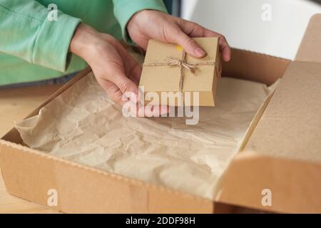 Primo piano di donna che tiene imballato la scatola piccola mentre la apre pacco Foto Stock
