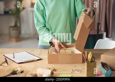 Primo piano della giovane donna che mette poco presente per il cliente in il pacco Foto Stock
