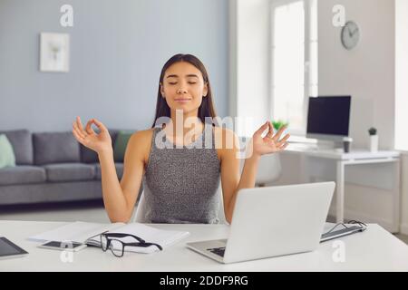 Calma donna di affari medita con i suoi occhi chiusi nel suo ufficio durante una pausa. Foto Stock