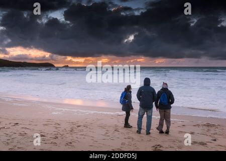 Una famiglia di vacanzieri che si trova sulla Fistral Beach guardando uno spettacolare tramonto a Newquay in Cornovaglia. Foto Stock