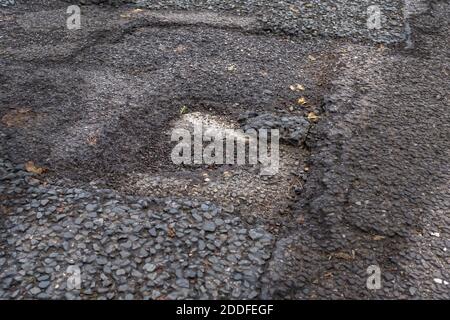 Buchi nella strada non riparata Inghilterra Foto Stock