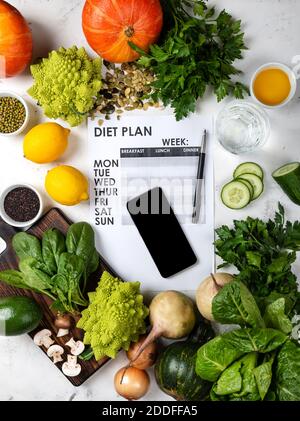 Smartphone e piano dieta sul set di fogli di cibo sano sul tavolo. Vista dall'alto Foto Stock