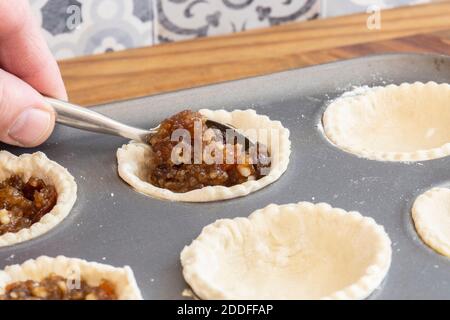 Pasta ripiena uomo con mangia per preparare torte mince. In una teglia metallica su legno Foto Stock