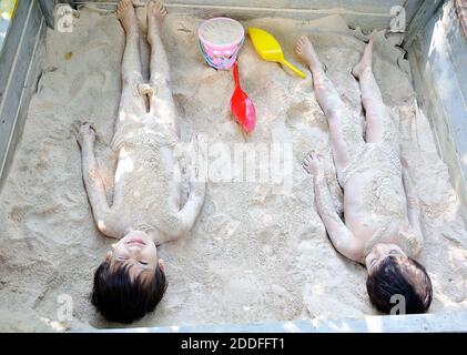 Due bambini maschi che giocano nella sabbia, nascondendo e coprendo i themselfs Foto Stock