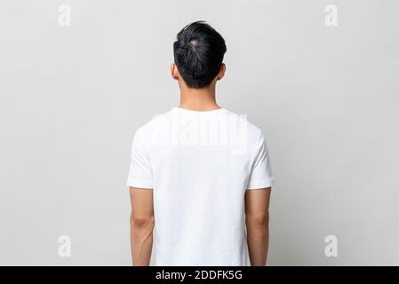 Vista posteriore di un giovane uomo che indossa una t-shirt bianca sfondo isolato grigio chiaro Foto Stock