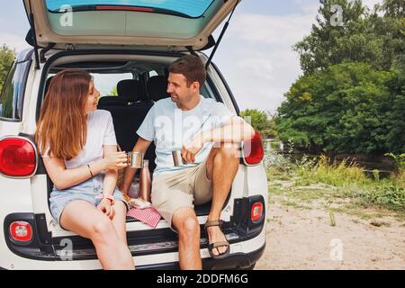 Uomo e donna seduti in un tronco della loro auto fare un picnic Foto Stock