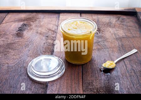 Un vaso di vetro aperto di marmellata fatta in casa e un cucchiaio con marmellata su un vecchio sfondo di legno scuro, concetto di sana colazione biologica Foto Stock