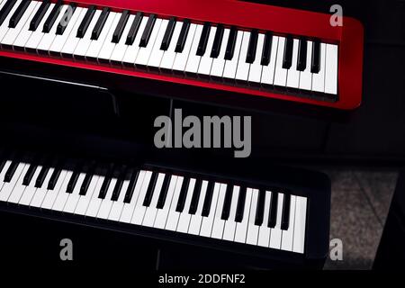 Sintetizzatori elettronici (tastiere a piano) primo piano con sfondo scuro. Belle tastiere musicali rosse e nere con tasti in bianco e nero. Foto Stock