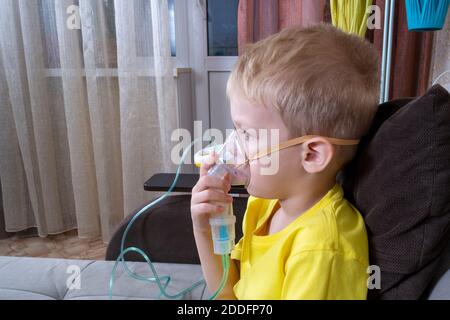 un ragazzo di 5-7 anni in una t-shirt prende un inalazione a casa Foto Stock