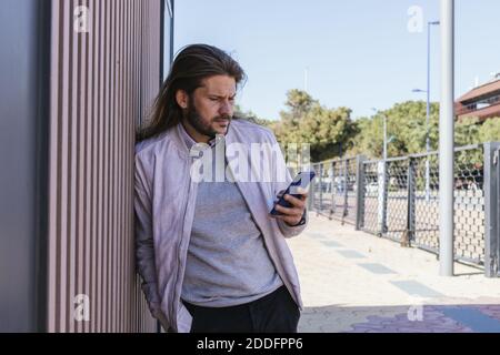 Un uomo appoggiato al muro con un mobile Foto Stock