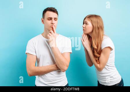 Foto di una giovane donna che prega tenendo le mani dentro un gesto di supplica che chiede qualcosa al marito contro di lei uno sfondo blu Foto Stock