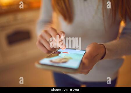 Donna che guarda l'immagine del profilo del giovane uomo su app di incontri e premendo il pulsante rosso "heart like" Foto Stock