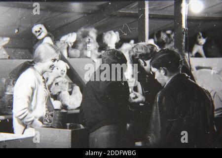 Bella fotografia in bianco e nero degli anni '70 di persone che si divertono al carnevale locale giocando un gioco. Foto Stock