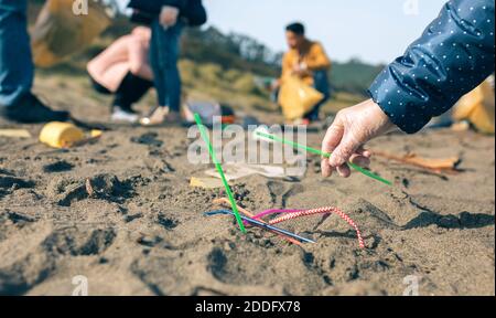 Donna che raccoglie cannucce sulla spiaggia Foto Stock