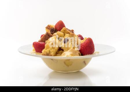 Panettone in pezzi con crema pasticcera, fragole e uvetta. Dessert italiano per Natale in piatto su sfondo bianco Foto Stock