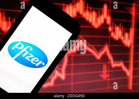 In questa illustrazione della foto è stato visualizzato un logo di Pfizer Pharmaceutical Company visualizzato su uno smartphone davanti a un cartoncino rosso grafico che indica un rallentamento Foto Stock