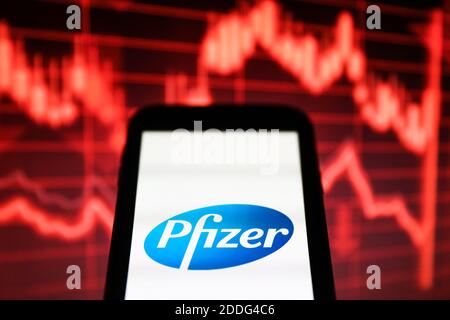 In questa illustrazione della foto è stato visualizzato un logo di Pfizer Pharmaceutical Company visualizzato su uno smartphone davanti a un cartoncino rosso grafico che indica un rallentamento Foto Stock