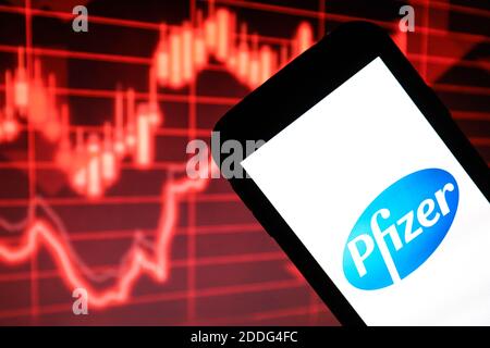 In questa illustrazione della foto è stato visualizzato un logo di Pfizer Pharmaceutical Company visualizzato su uno smartphone davanti a un cartoncino rosso grafico che indica un rallentamento Foto Stock