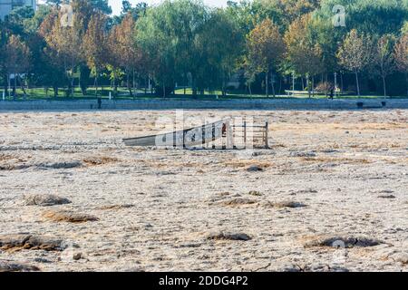 Una barca di legno nel fiume Zayandeh siccità, o Zayandeh-Rood o Zayanderood, in inverno, Esfahan, Iran con sfondo di si-o-seh pol ponte. Foto Stock