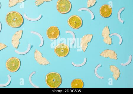 Lotto di frutta secca chip arance, cocco e ananas sparsi su sfondo blu. Patatine di frutta. Concetto di alimentazione sana, snack, senza zucchero. Vista dall'alto, Foto Stock