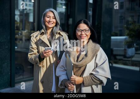Gioiose donne con taccuini in piedi per strada Foto Stock