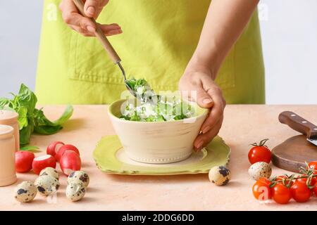 Donna che mescola insalata di riso con verdure sul tavolo Foto Stock