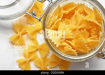 Vaso in vetro con pasta cruda su sfondo chiaro Foto Stock