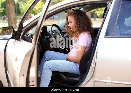 Donna afro-americana incinta che sente contrazioni alla nascita in auto Foto Stock