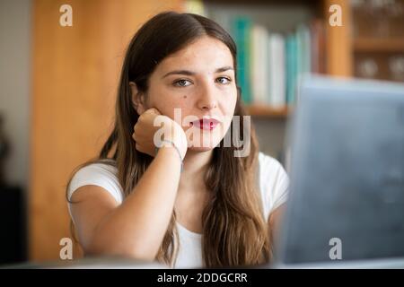 Giovane donna che lavora al computer in biblioteca Foto Stock