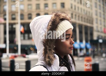 Vista laterale della giovane donna afroamericana in outerwear a piedi Lungo la strada a New York e godendo di una passeggiata Foto Stock